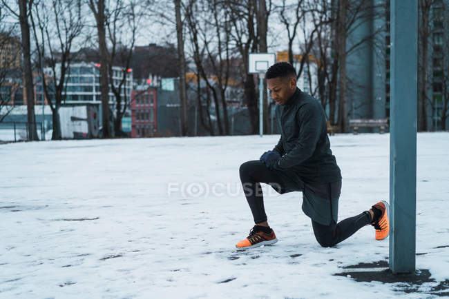 Vista laterale dell'uomo sportivo che riscalda le gambe al parco giochi — Foto stock
