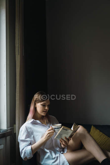 Вид збоку жінки, читаючи книгу про тренера в домашніх умовах — стокове фото