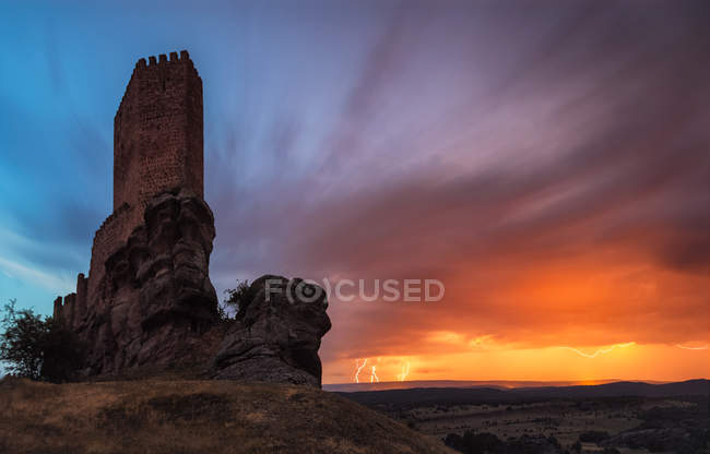 Vista panorámica de la torre del castillo construida en la colina sobre el fondo del cielo puesta del sol - foto de stock