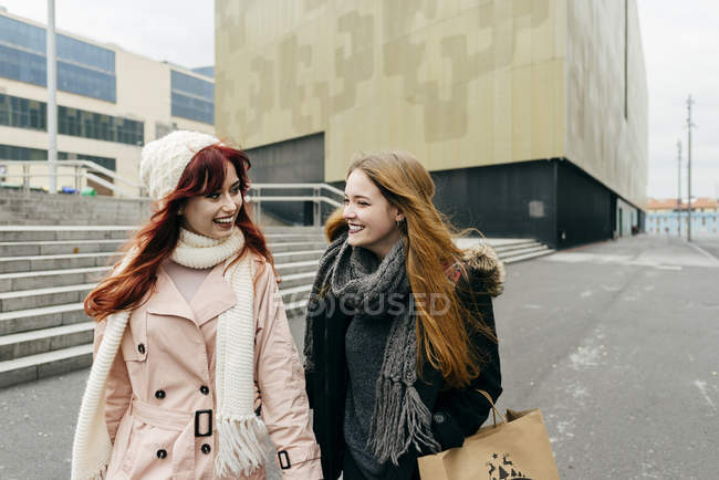 Retrato de duas mulheres rindo andando na rua e olhando para cada uma — Fotografia de Stock