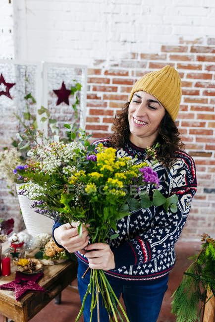 Портрет усміхненої жінки, що влаштовує квіти в квітковому ательє — стокове фото