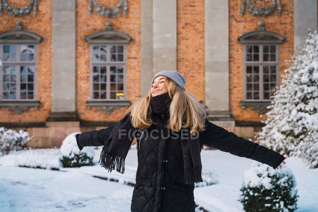 Портрет блондинки, що позує широко простягнуті руки в зимовому місті — стокове фото