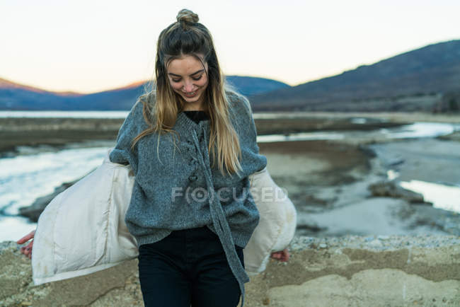 Jovem mulher sorridente em roupas quentes andando em terreno rochoso em montanhas . — Fotografia de Stock