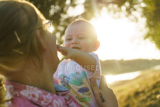 Portrait of child touching mothers face in summer park — Stock Photo