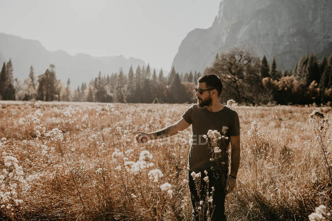 Portrait of man walking on dry meadow and palming plants — Stock Photo