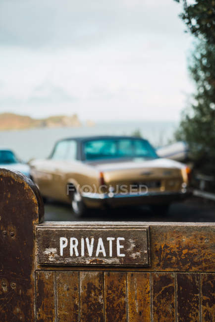 Close up view of private sign on fence and vintage car parked behind — Stock Photo