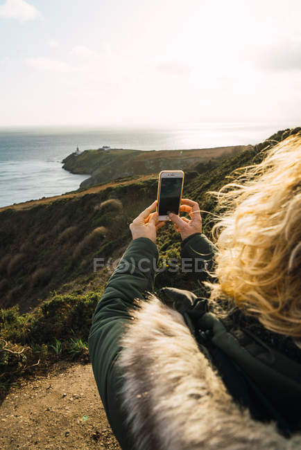 Sobre a visão do ombro da mulher tomando tiros de paisagem marinha — Fotografia de Stock