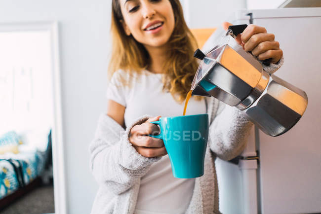 Кукурудзяна жінка наливає каву в синю чашку — стокове фото