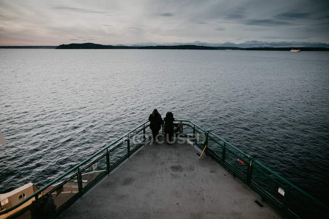 Вид сзади пары, стоящей вместе на носу корабля посреди океана — стоковое фото