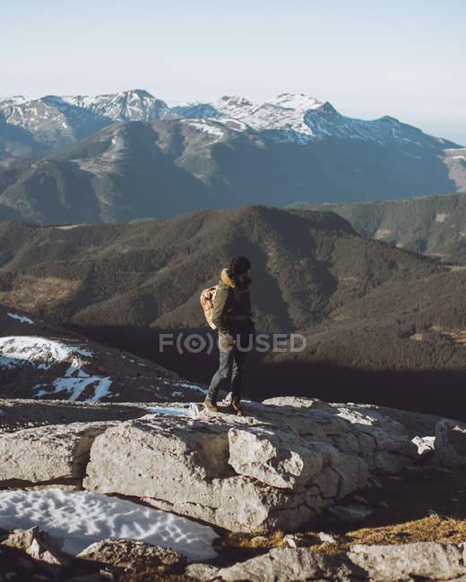 Vista lateral del hombre en ropa de abrigo mirando las montañas nevadas - foto de stock