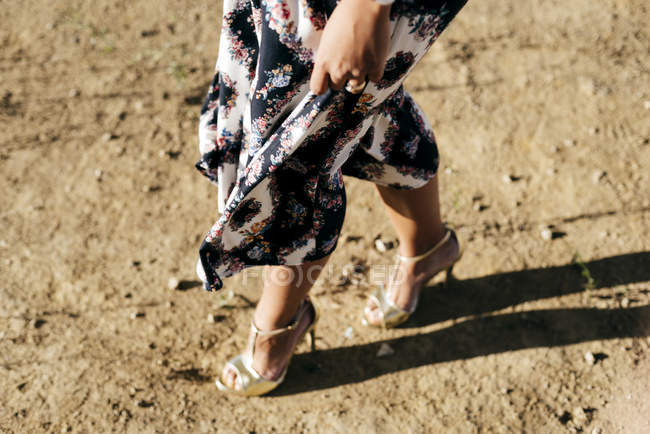 Нижняя часть женщины в красивом платье прогулка по земле в солнечный день — стоковое фото