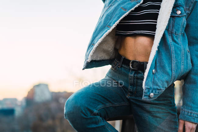 Midsection of fit woman wearing stylish jeans and denim jacket posing outside. — Stock Photo