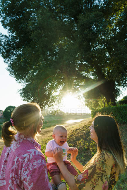 Щаслива лесбіянка пара пудинг з дитиною на парковому газоні — стокове фото