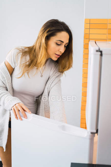 Вид збоку жінки, що відкриває холодильник вдома — стокове фото