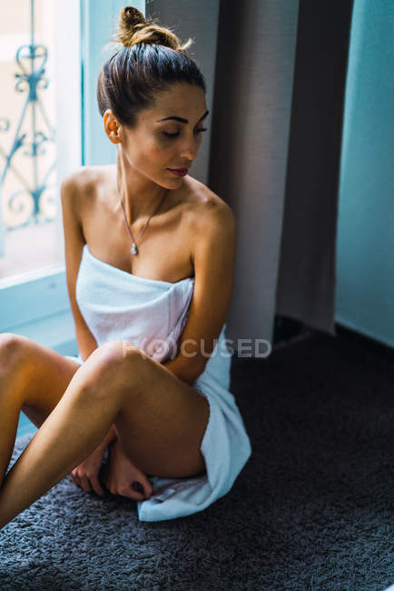 Ritratto di donna in asciugamano seduta sul davanzale della finestra — Foto stock