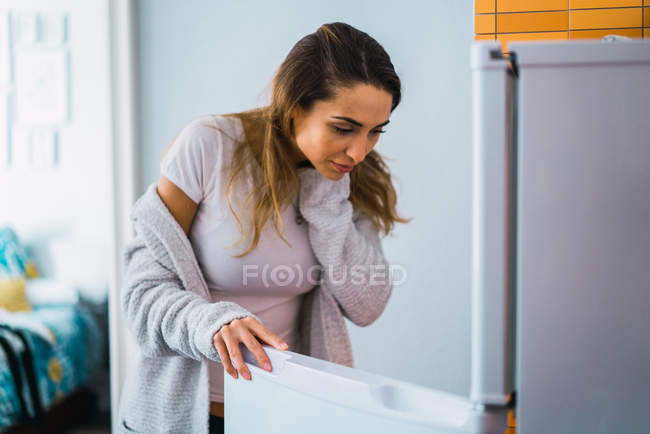 Mulher bonita na abertura do frigorífico em casa — Fotografia de Stock