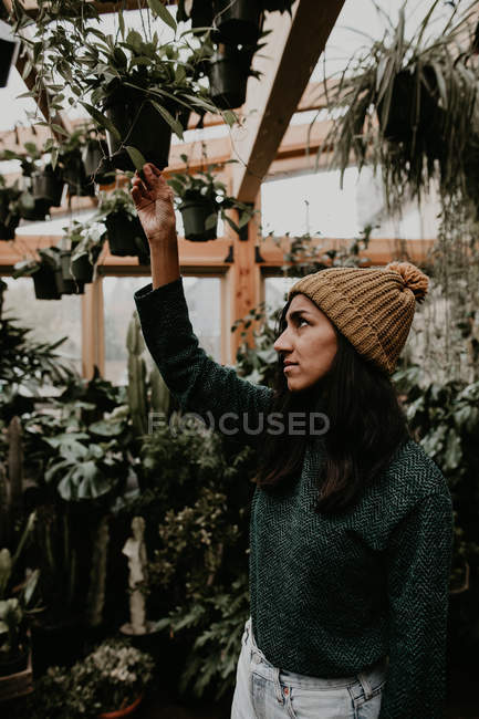 Seitenansicht einer Frau, die Pflanzen im Gewächshaus sieht — Stockfoto