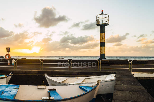 Small boats and rusty metal pipe at seaside — Stock Photo