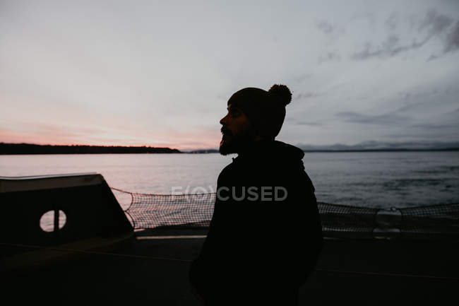 Silhouette eines Mannes, der auf einem Schiff vor dem Hintergrund des Meeres in der Dämmerung steht — Stockfoto