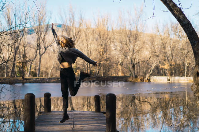 Портрет веселой женщины, прыгающей на пирс в парке — стоковое фото