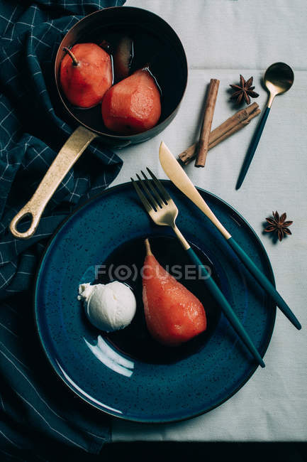 Vue de dessus des poires braconnées dans le vin rouge servi sur une assiette en céramique — Photo de stock