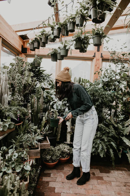 Seitenansicht eines Mädchens, das Pflanzen im Gewächshaus betrachtet — Stockfoto