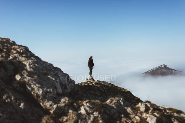 Hombre en el acantilado rocoso en las nubes - foto de stock