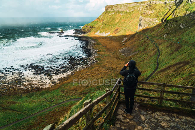 Вид ззаду на туриста, що стоїть з точки зору і знімає пейзаж — стокове фото
