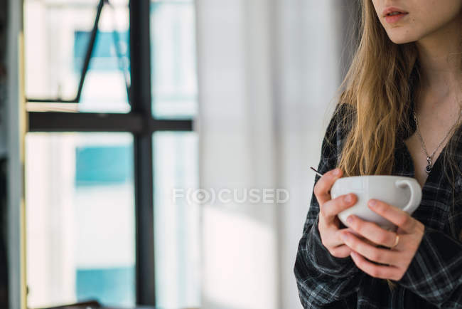 Cultivo chica rubia con taza de café en casa - foto de stock