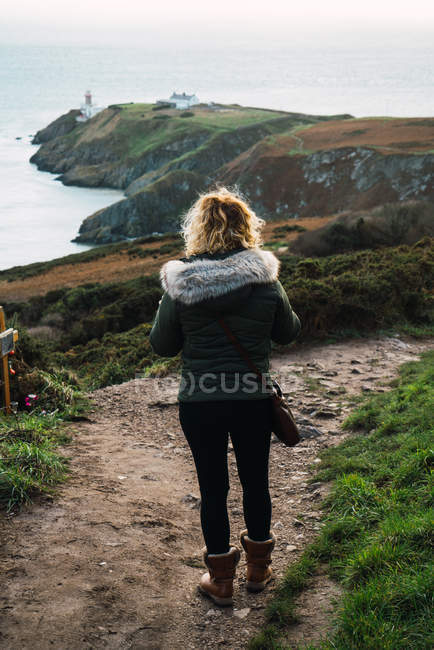 Vue arrière de la femme marchant sur la côte — Photo de stock