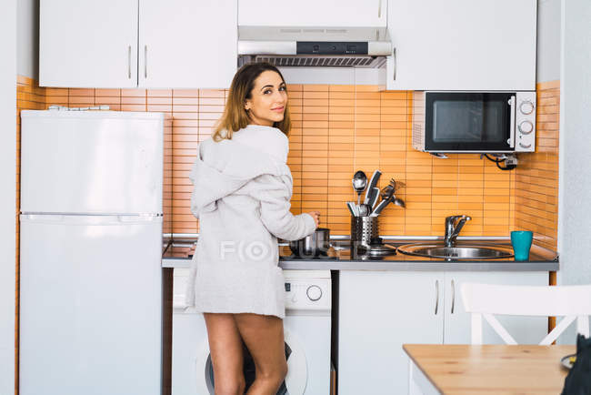 Mulher jovem cozinhar na cozinha e olhando para a câmera — Fotografia de Stock