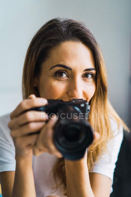 Portrait of woman with camera looking at camera — Stock Photo
