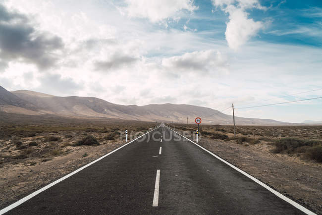 Perspective view to asphalt road leading to mountains in desert — Stock Photo