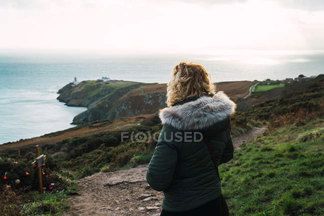 Rear view of woman posing at coastal hills on foggy day — Stock Photo