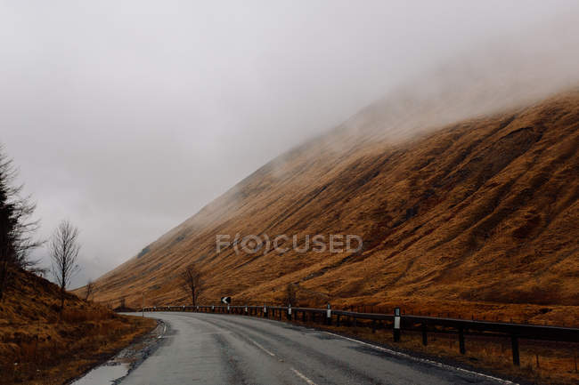 Вид на мокру асфальтову дорогу в туманних горах — стокове фото