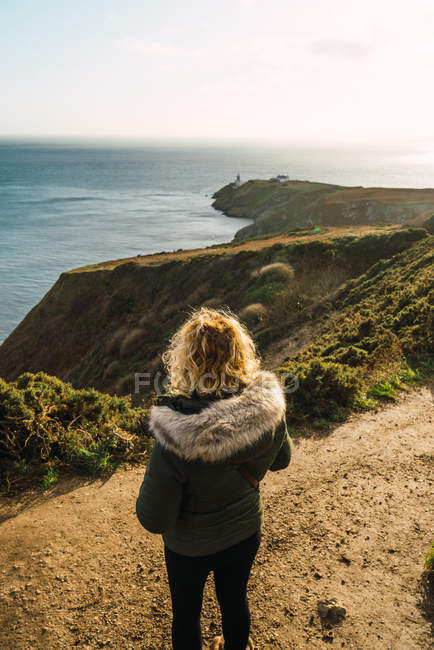Rückansicht einer Frau, die auf Hügeln an der Küste steht — Stockfoto