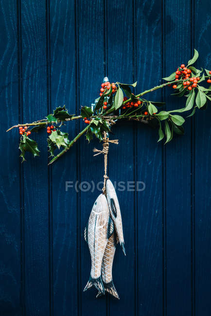 Zweige mit Beeren und Fischdekoration hängen an blauer Holztür. — Stockfoto