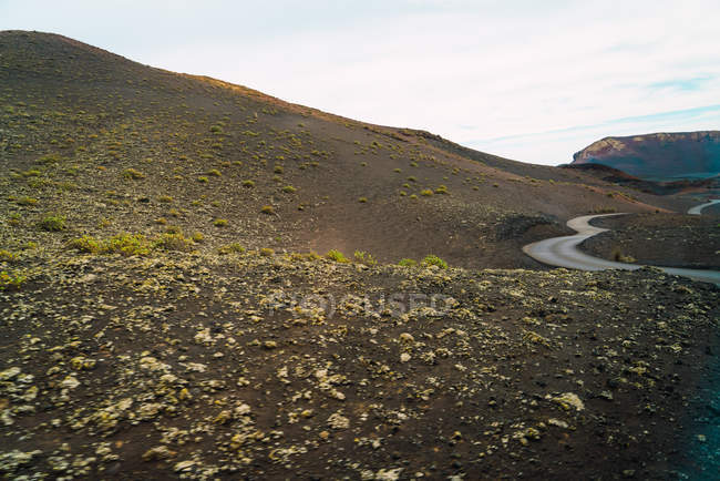 Vue sur les collines et la petite route asphaltée par temps nuageux — Photo de stock