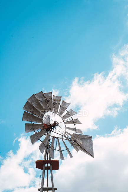 Vista ad alto angolo di vecchio mulino a vento in metallo rotante su sfondo di cielo blu
. — Foto stock