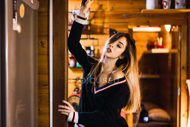Junge Frau posiert verführerisch in schwarzem Pullover vor dem Hintergrund des Hausinneren. — Stockfoto