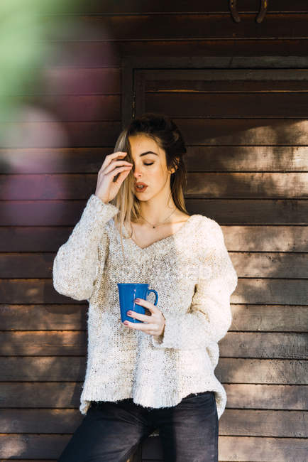 Ritratto di donna bionda in posa con gli occhi chiusi e una tazza di caffè in mano — Foto stock
