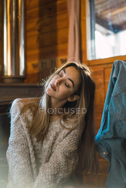Блондинка, сидящая на полу шале и позирующая — стоковое фото