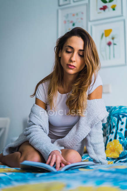 Porträt einer Frau, die Buch auf dem Bett liest — Stockfoto