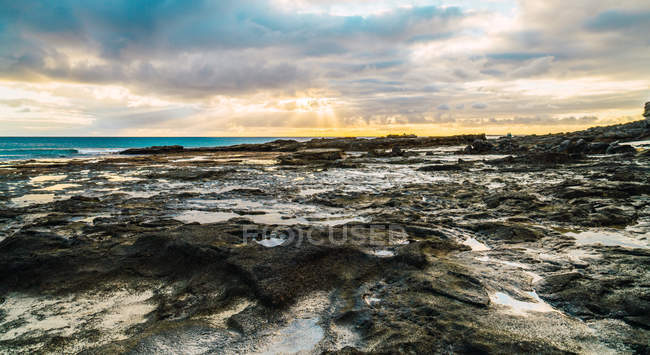 Amazing shoreline rock formations on background of scenic cloudy sky — Stock Photo