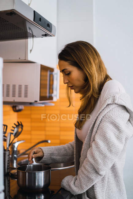 Вид збоку молодої жінки, що готує на кухні — стокове фото