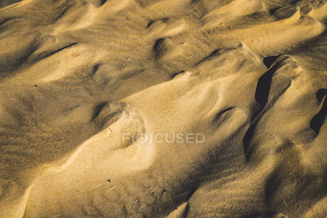 Sfondo astratto di sabbia dorata che forma superficie increspata alla luce del sole . — Foto stock