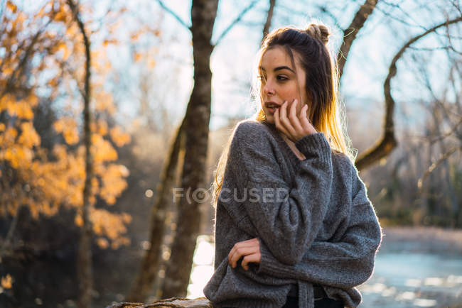 Vue latérale de la femme rêveuse posant dans les bois automnaux — Photo de stock
