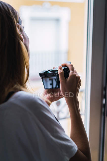 Sopra la spalla vista del fotografo con fotocamera alla finestra — Foto stock
