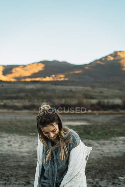 Retrato de una mujer joven quitándose el abrigo en el prado - foto de stock