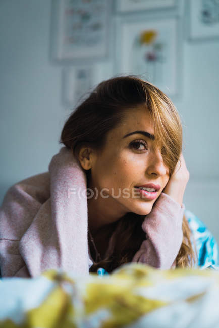 Portrait of woman lying in bed and looking at camera — Stock Photo